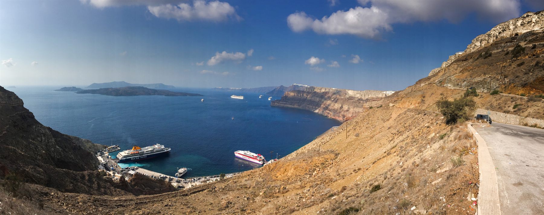 Cruise ships anchored below the cliffs of Santorini, seen from the clifftop road