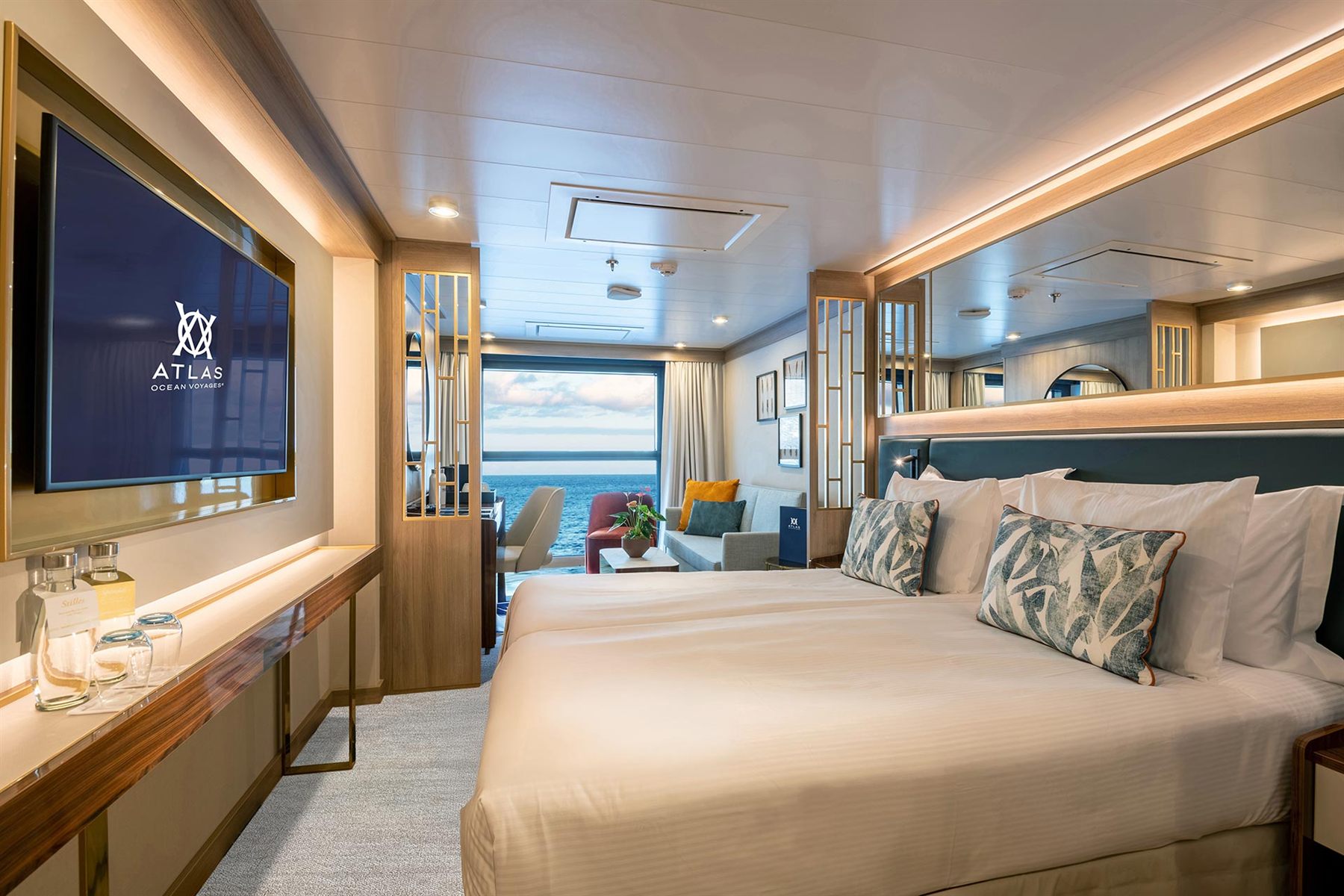 An Atlas Ocean Voyages stateroom with a king bed and balcony doors